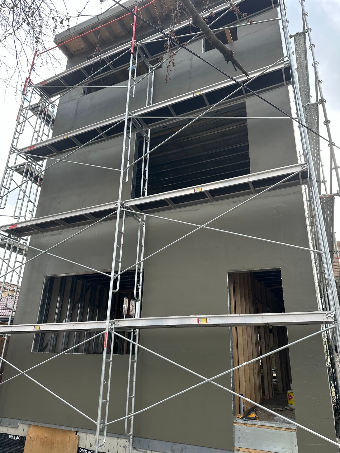 Base coat applied across a multi-storey wall with scaffold in place