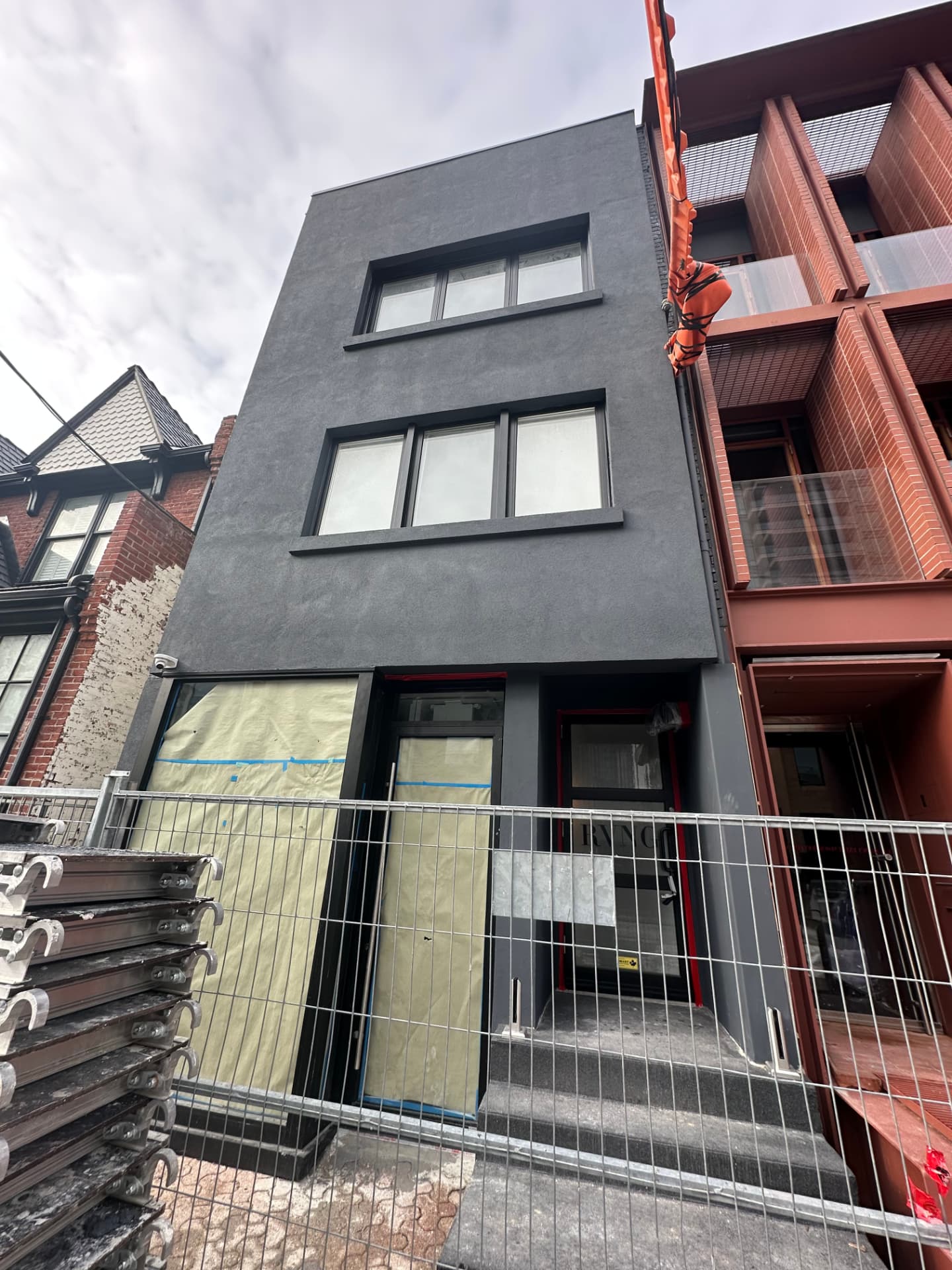Charcoal stucco infill facade with black window surrounds