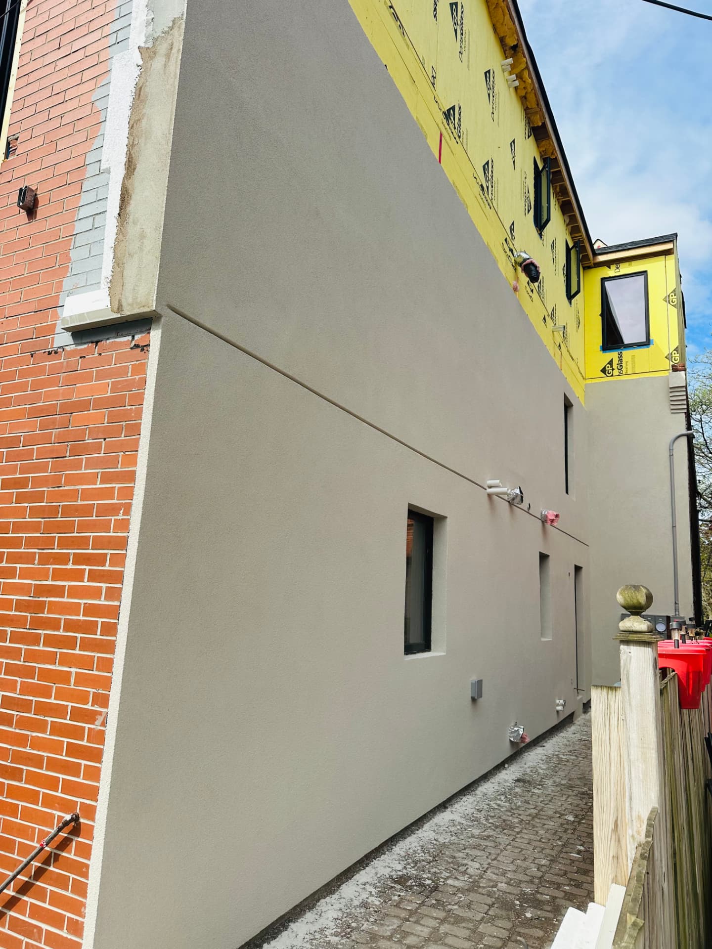 Greige stucco wall running the full length of a narrow laneway
